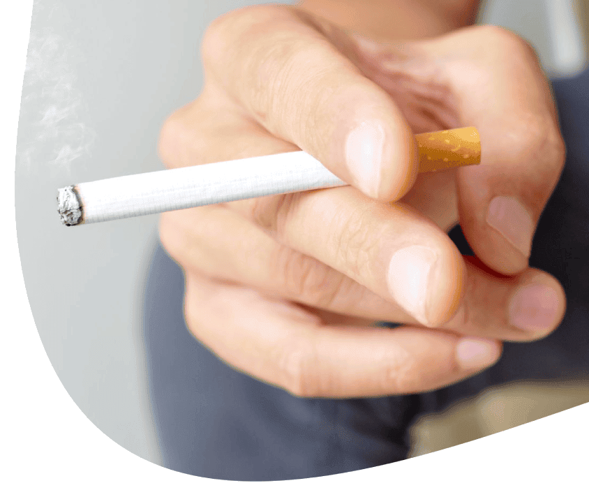 Ruka držící zapálenou cigaretu, důraz na kouření tabáku.